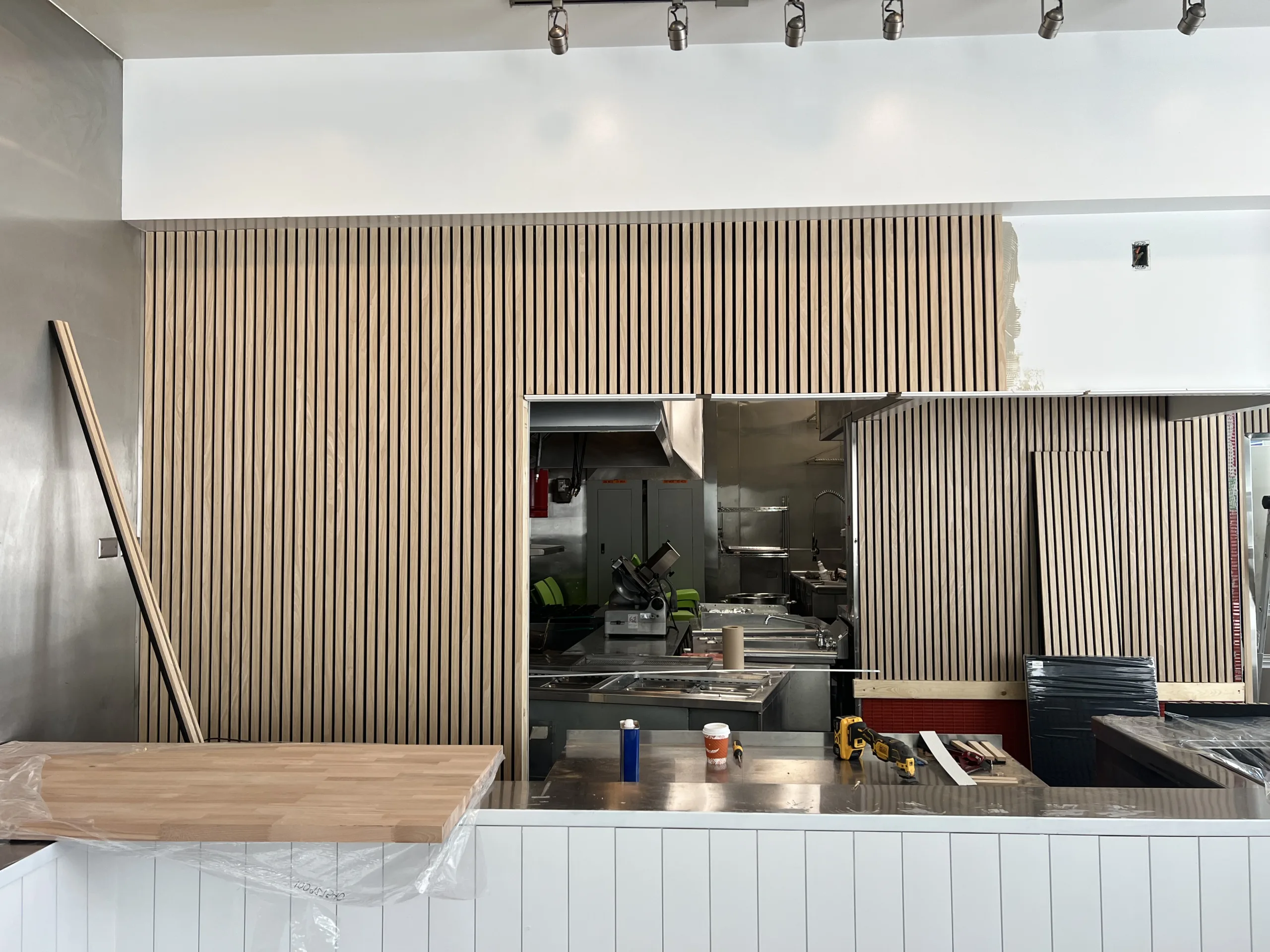 Wood slat panel detail around service opening in Chicago bakery remodel