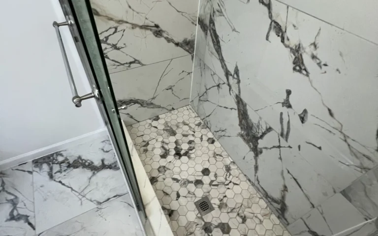 Finished shower with white marble tiles and hexagonal floor mosaic