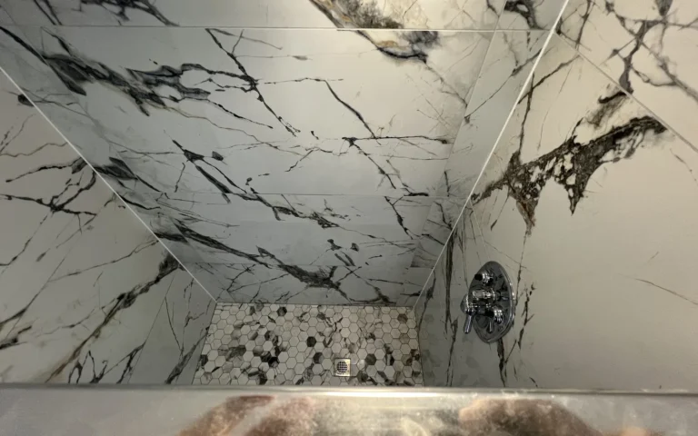 Finished shower with white marble look wall tiles and hexagonal floor mosaic