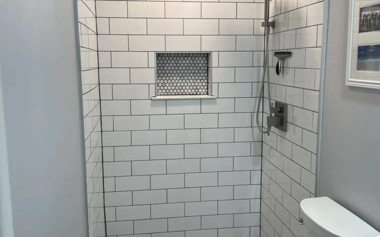 Finished walk in shower with white subway tiles rain shower head and hexagonal floor accents