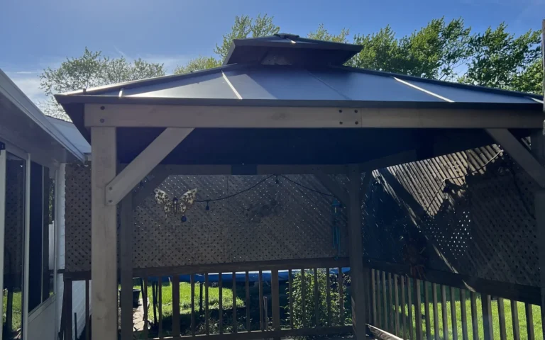 Wooden gazebo with metal roof and lattice sides on a deck