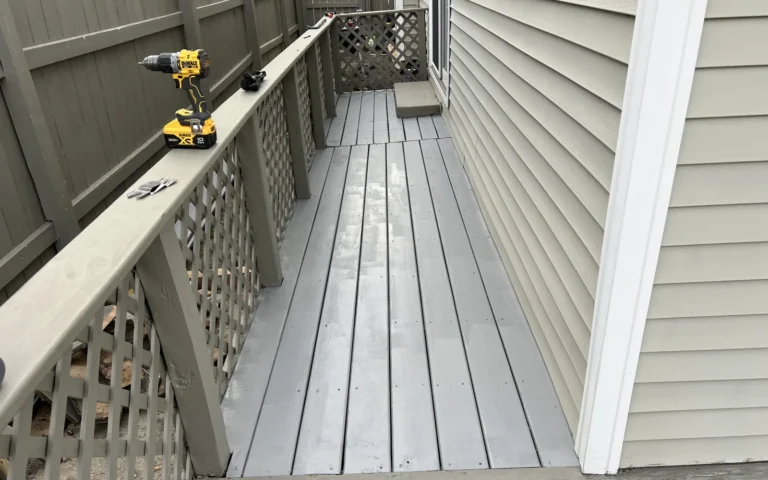 Grey painted wooden deck walkway with power drill on railing during renovation