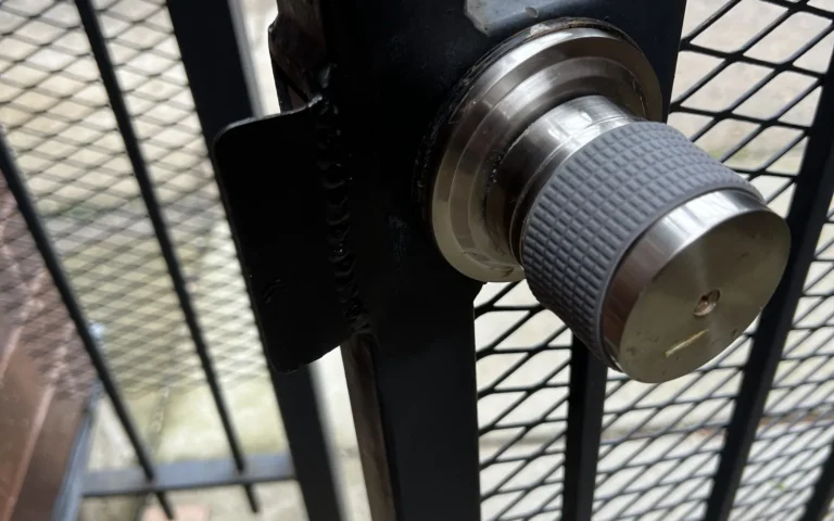Stainless steel gate lock knob installed on black metal mesh gate