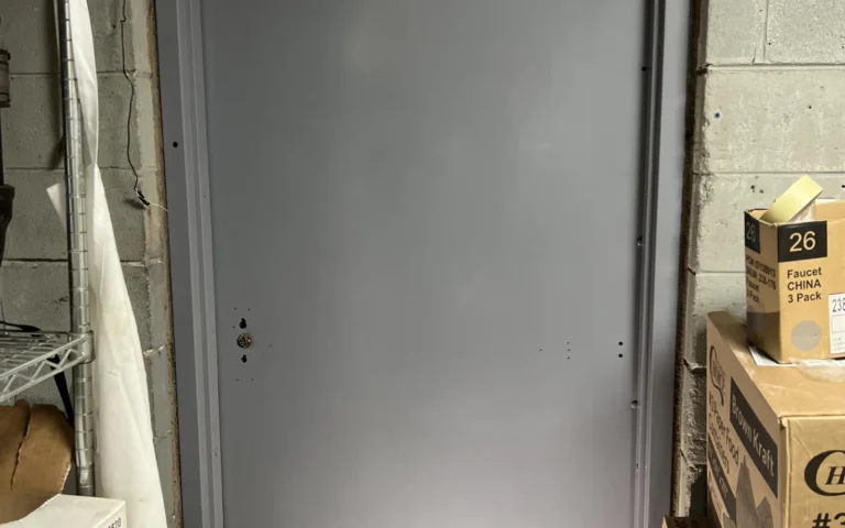 Grey metal exit door installed in concrete wall with storage shelves