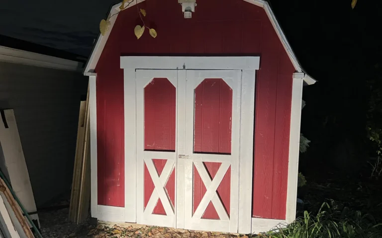 Red shed with white trim and double barn doors after carpentry repair