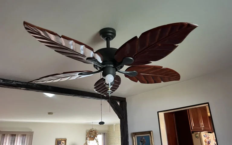 Dark bronze ceiling fan with wooden leaf blades installed in a home interior