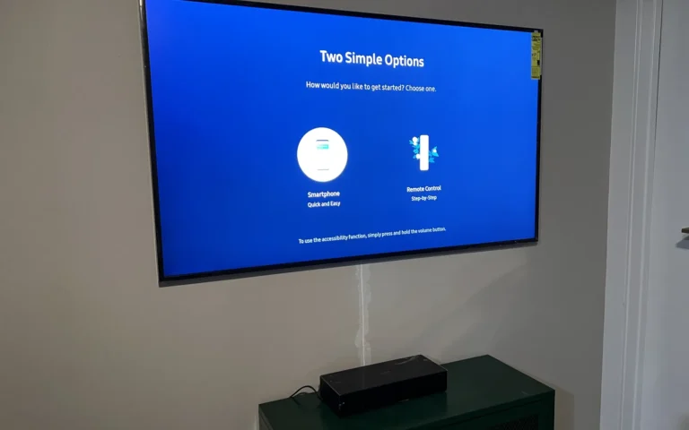 Mounted flat screen TV on wall with soundbar on green cabinet below