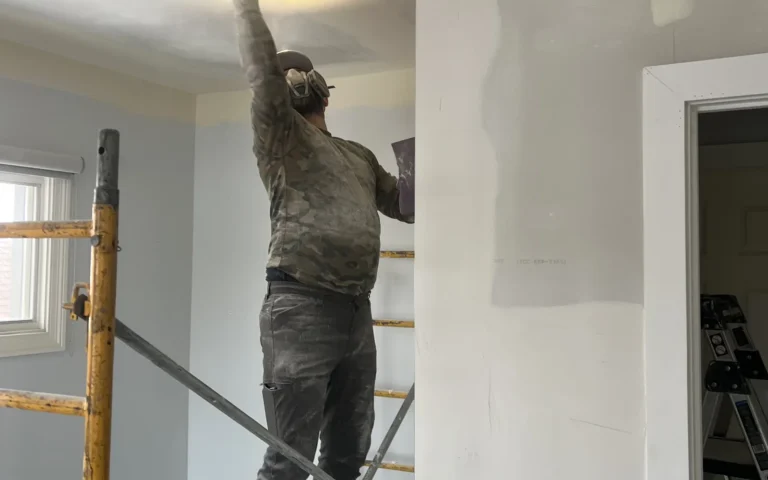 Handyman sanding ceiling on scaffolding during home renovation