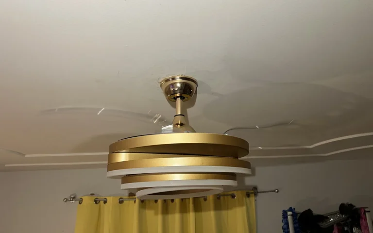 Gold and white ceiling fan with light rings installed and spinning in a room