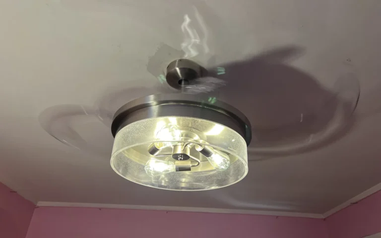 Installed modern ceiling fan with lights on spinning in a room with pink walls