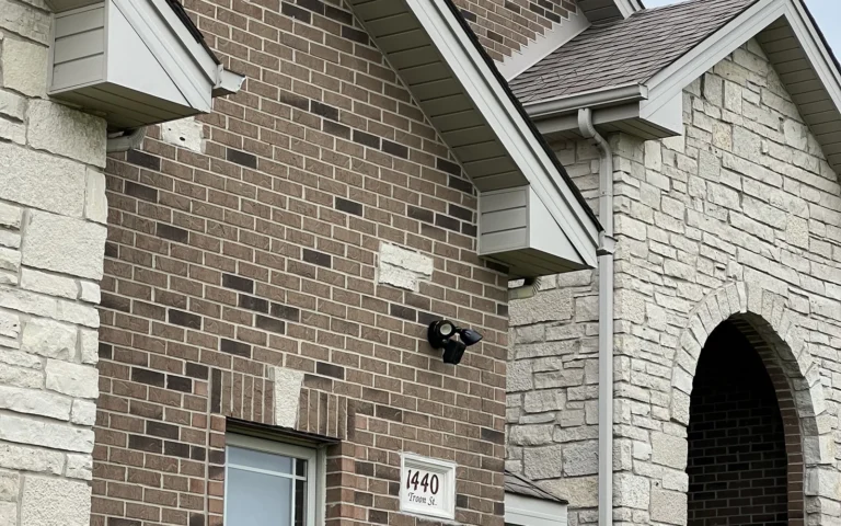 Brick home exterior with black floodlight and lantern fixture near arched entryway