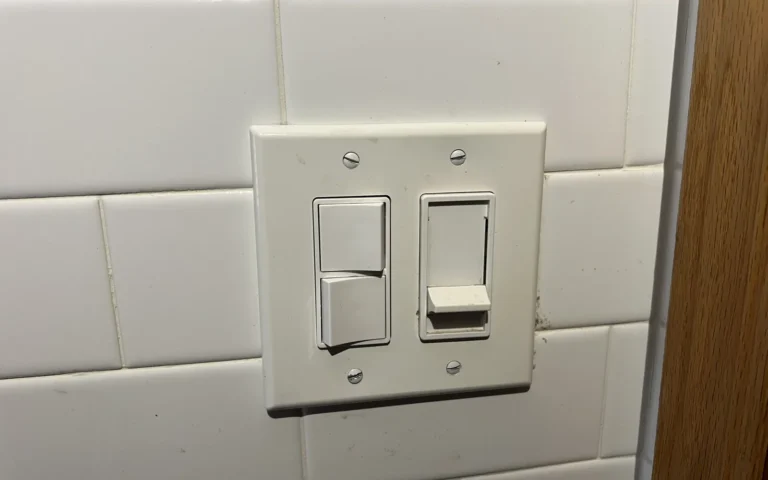 White double light switch plate on subway tile wall with toggle and dimmer switches