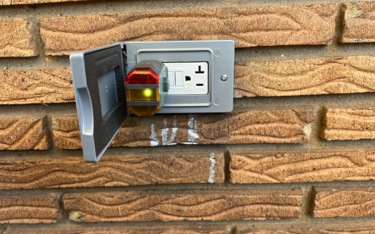 Outdoor GFCI outlet test on brick wall with circuit tester plugged in