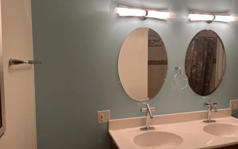 Finished bathroom vanity with dual sinks oval mirrors and modern lighting