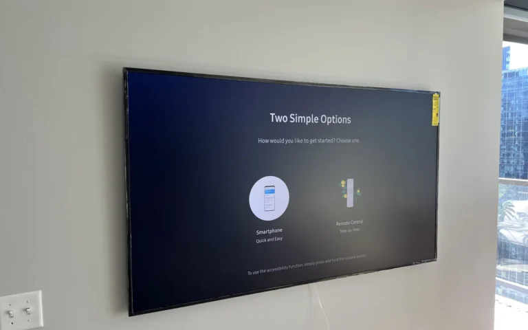 Wall mounted flat screen TV displaying setup menu options in a modern room with city view