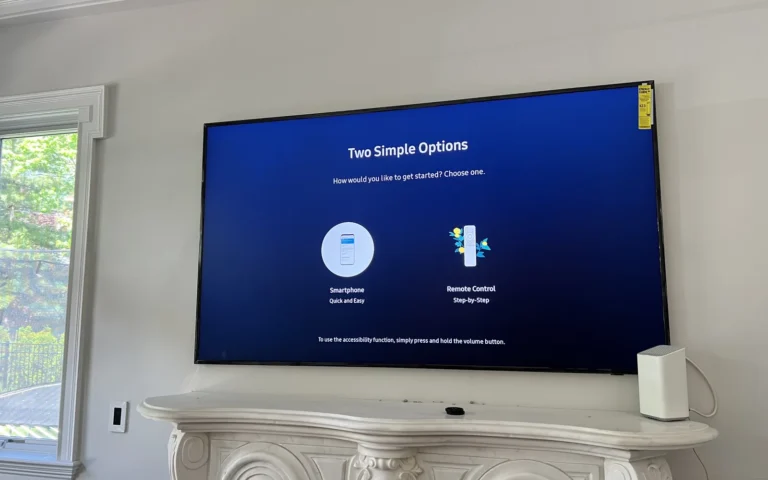 Large TV mounted above white fireplace mantel showing setup screen