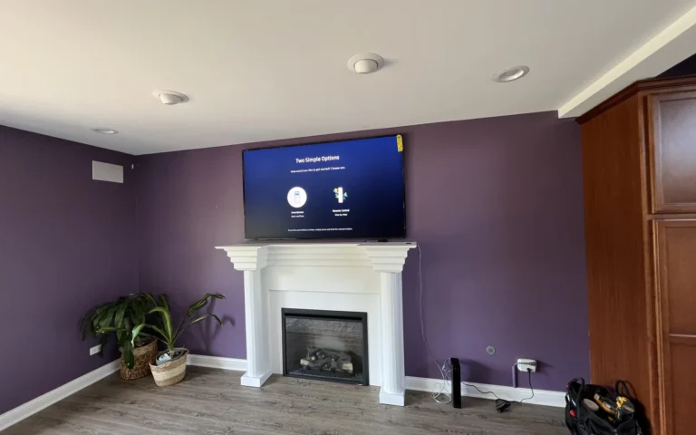 TV mounted above white fireplace in purple living room with tool bag