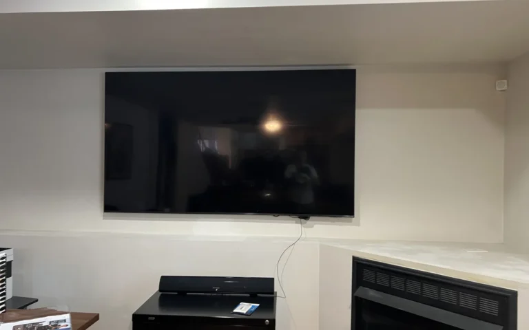 Flat screen TV mounted on wall above soundbar and fireplace