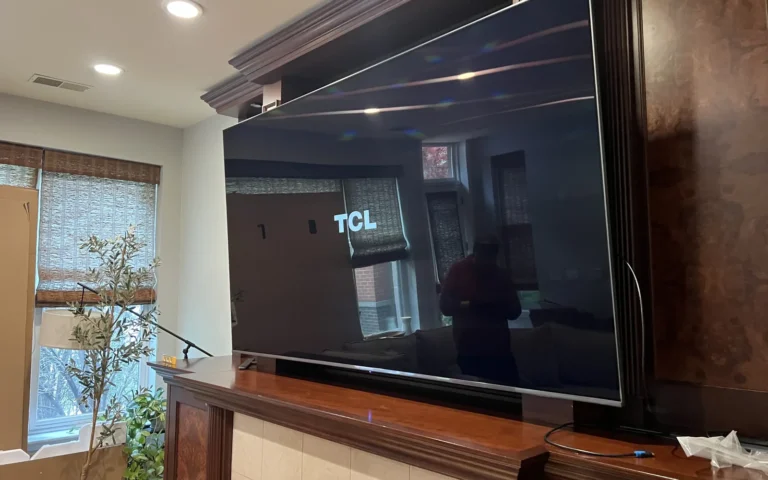 TCL TV mounted above fireplace mantel in living room
